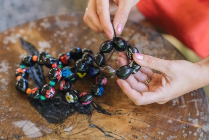 艶やかなククイの実をつなぎ合わせ、鮮やかな模様が映えるブレスレットを手に取る様子。