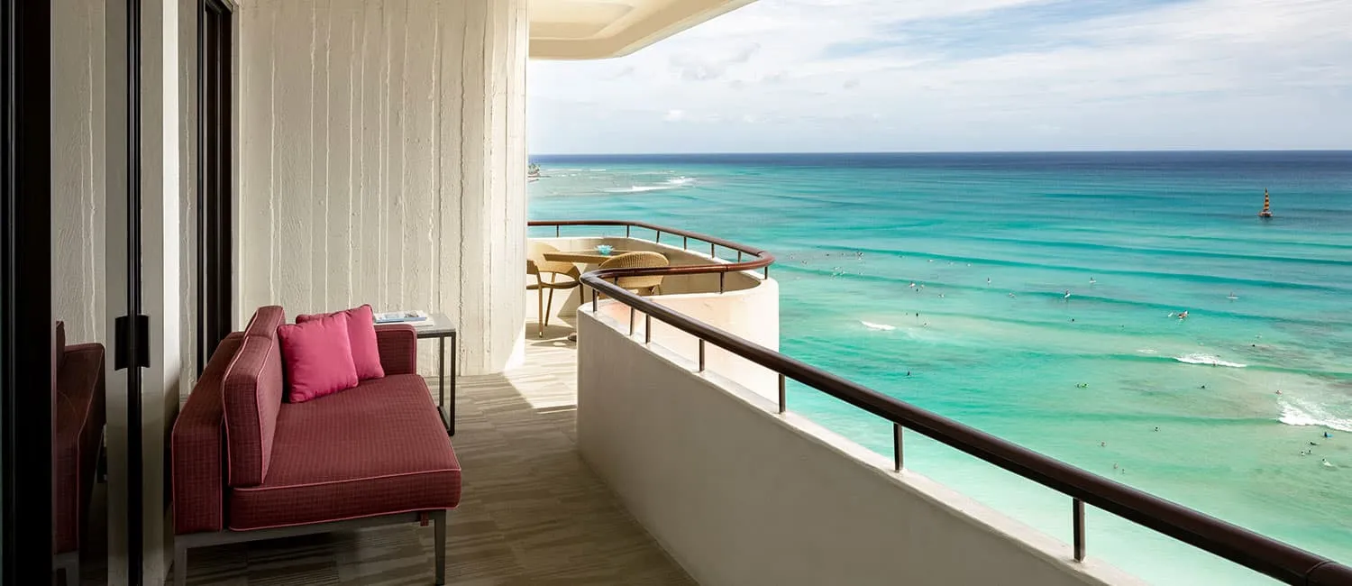 ピンクのソファが置かれたアリイスイートのバルコニーからの海の眺め