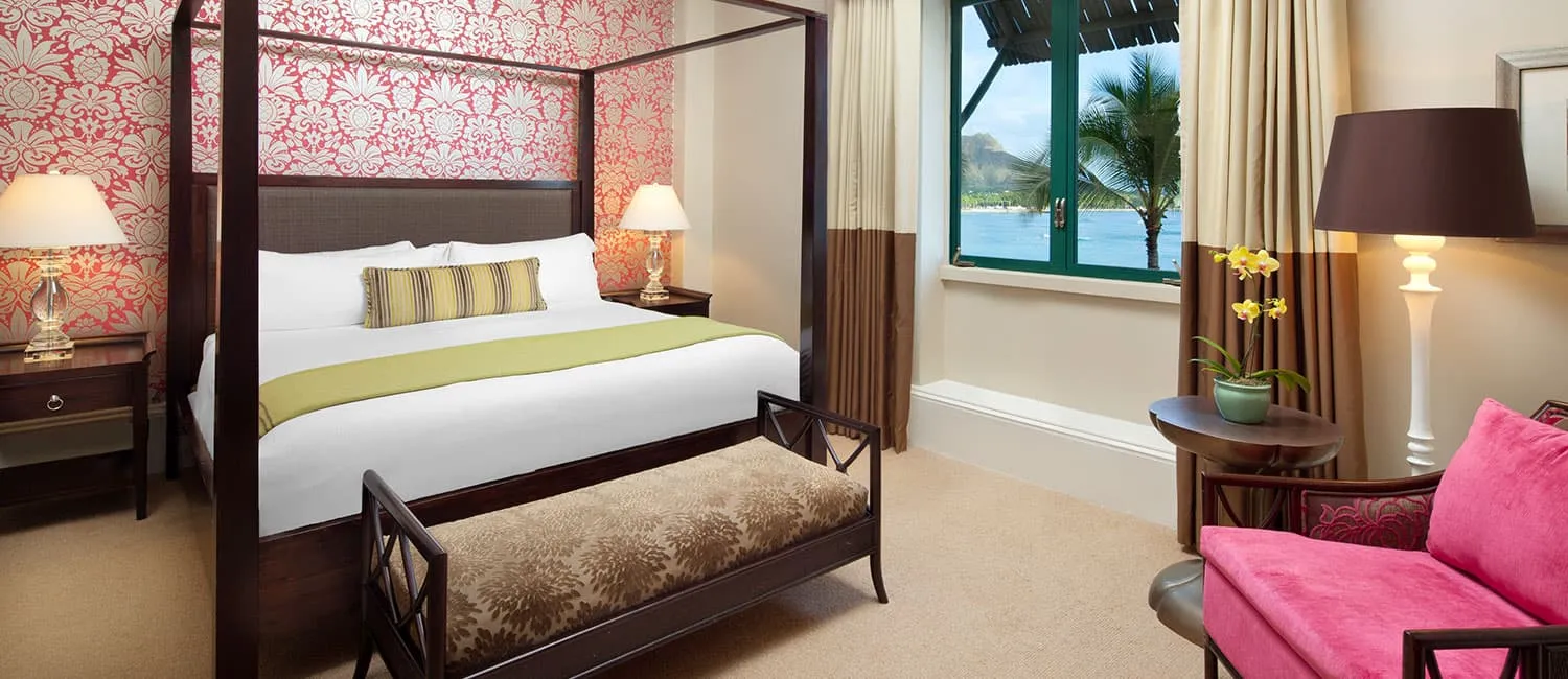 赤い壁紙と大きな窓が特徴のベッドルーム。窓の外には海が広がる