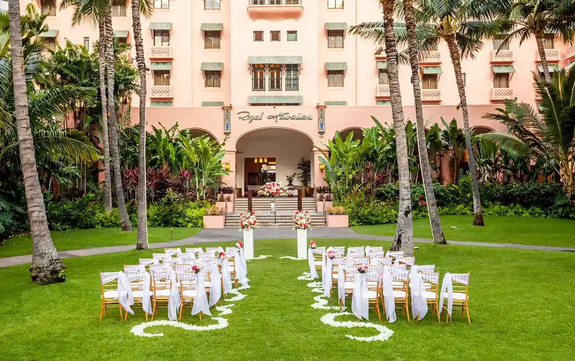 ヤシの木に囲まれたオーシャンフロントの芝生に、白いカクテルテーブルを配置したガーデンレセプション